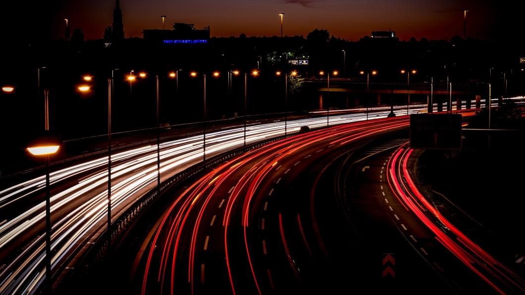 Auto's rijden 's avonds op de snelweg. Je ziet strepen van wit en rood licht omdat de fotograaf een lange sluitertijd heeft gebruikt.